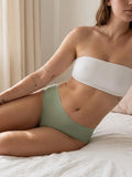 Menstruatie ondergoed groen, gedragen high waist brief in een ruimer lifestylebeeld op bed